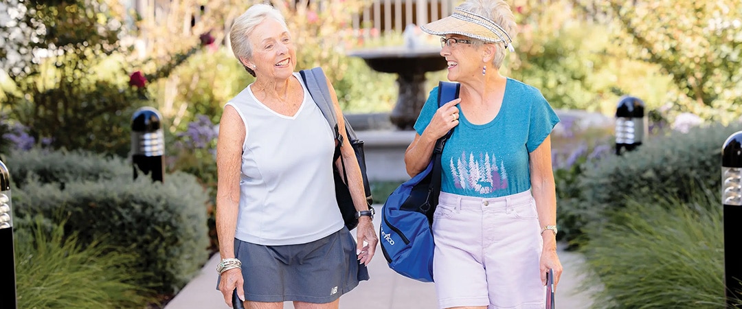 Two ladies walking together with pickleball bags