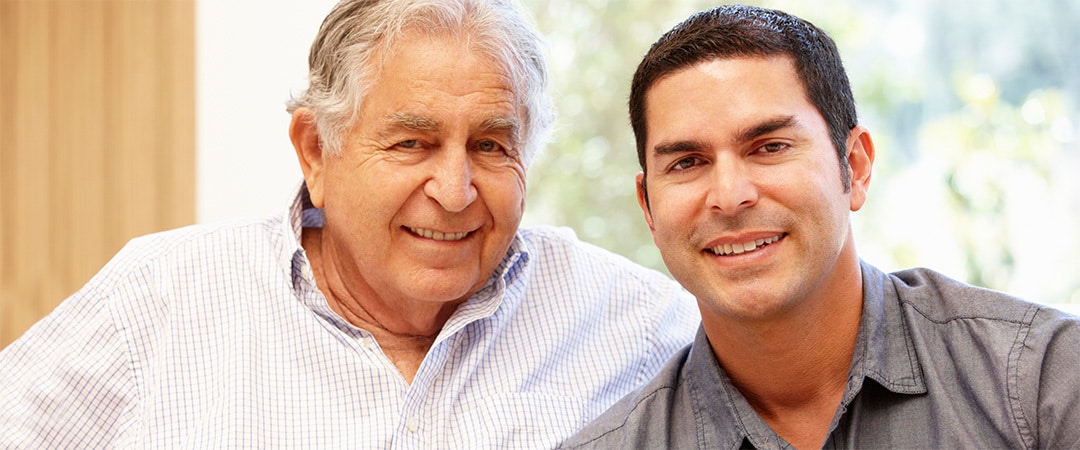 A son and father smiling together in a room.